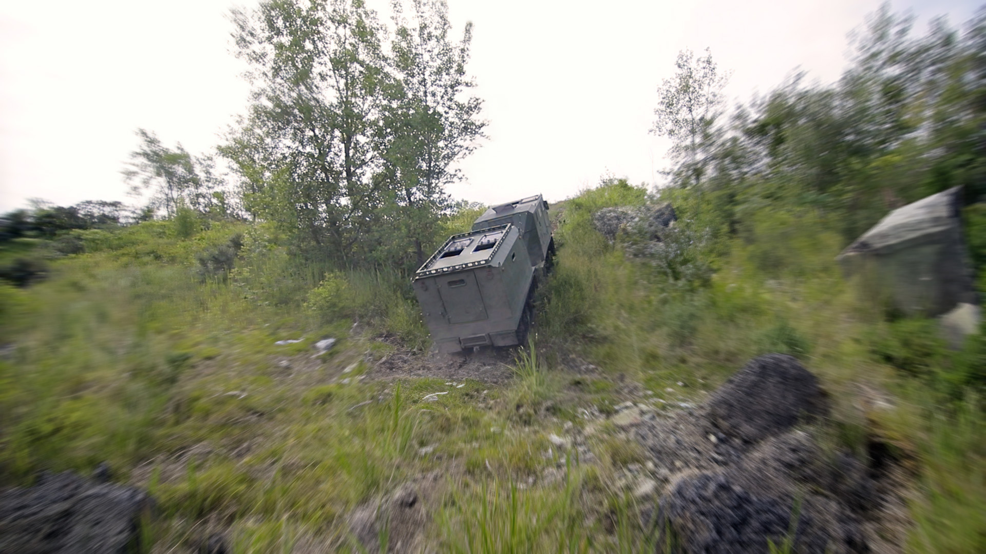 Voyager D12 climbing a rocky incline through brush