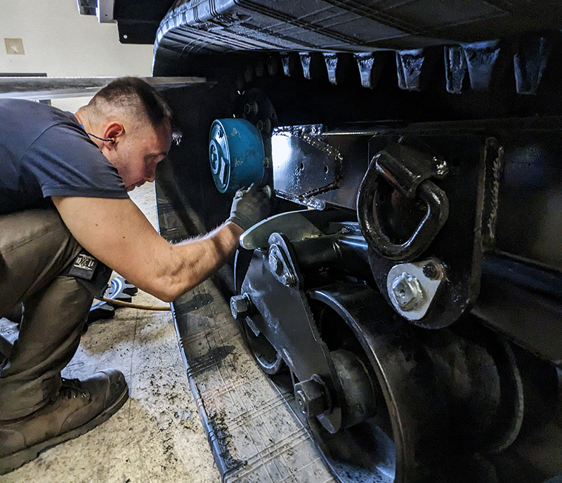 UTV technician servicing a track and suspension assembly