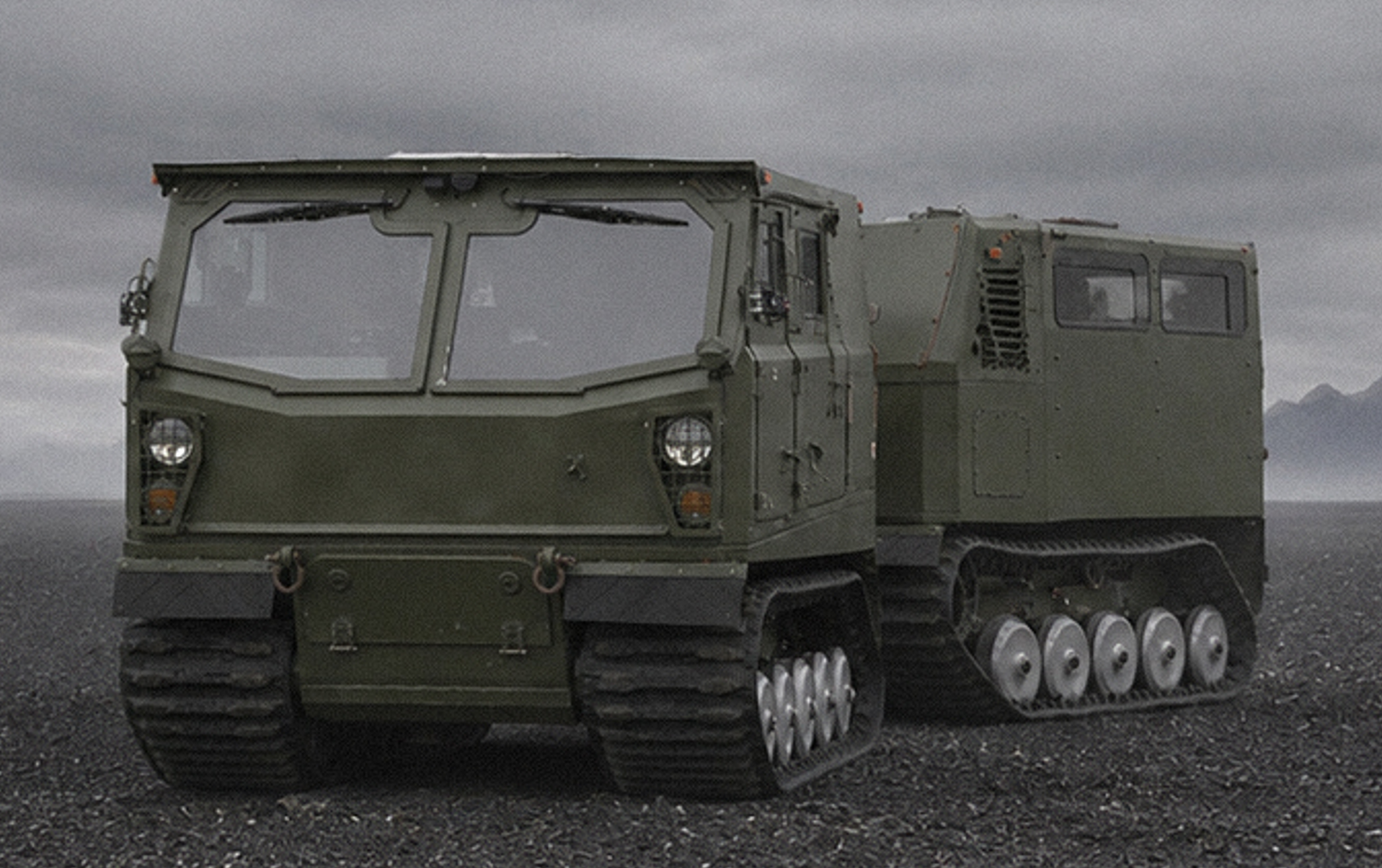 Voyager D12 articulated tracked carrier on dark volcanic terrain, front three-quarter view